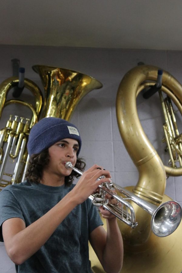 Cole Nashan practices playing his trumpet in the band room for his internship