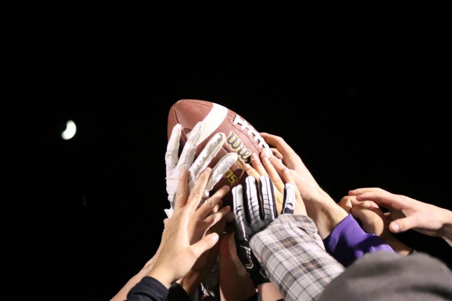 Seniors hold the game ball in the air victorious