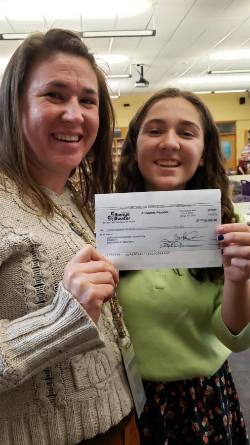 Green Initiative adviser Alecia Jongeward and team member Stella Davis hold the check for $15,000 from Sabanye Stillwater, which will help them install solar panels at Park High School, in the library on Nov. 18.