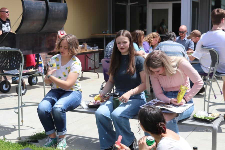 Summer Melin, Libby Kinsey and Emma Warhank eat during the summer barbeque in the courtyard.
