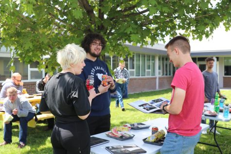 Julie Waldron, Gabe Holmes and Robert Durgan gather around the newly released yearbook during the senior BBQ on June 3.
