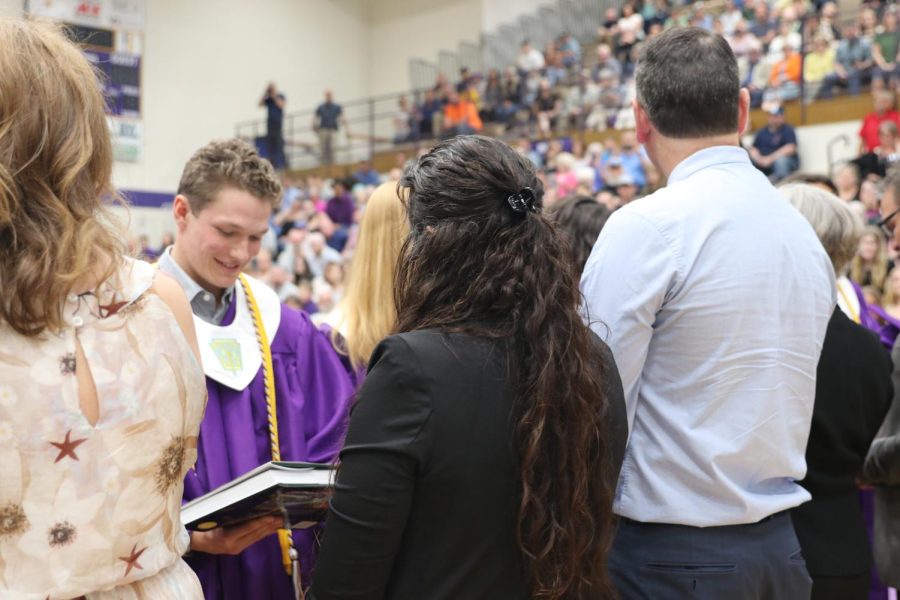 Liam Higgins looks at a book his fifth grade teacher, Chris Pavlovich, gave him during the robing ceremony.