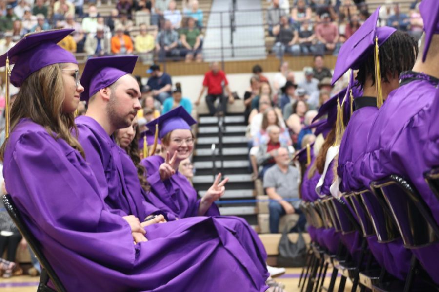 Coral Horn shares a peace sign during the graduation ceremony while Alejandra Kaliher-Tirado and Josh Jerde face forward.