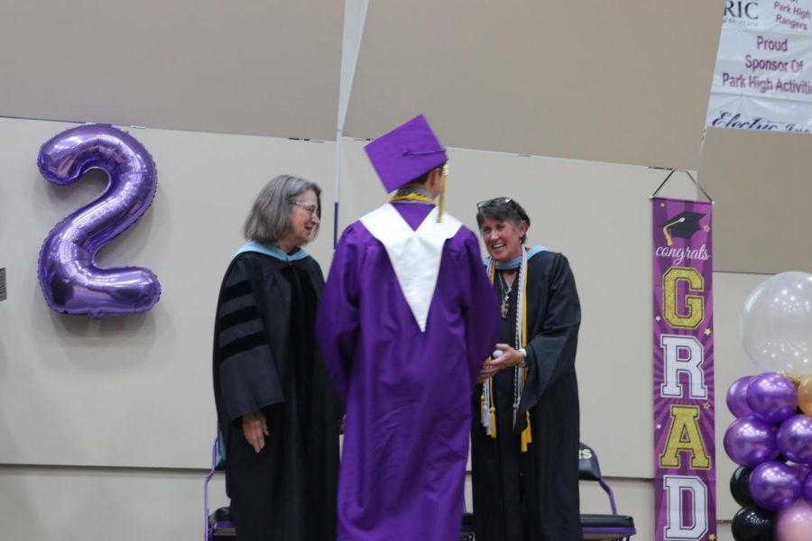 Principal Dust laughs as she receives yet another golf ball from a senior crossing the stage to graduate. Superintendent Lynne Scalia looks on.