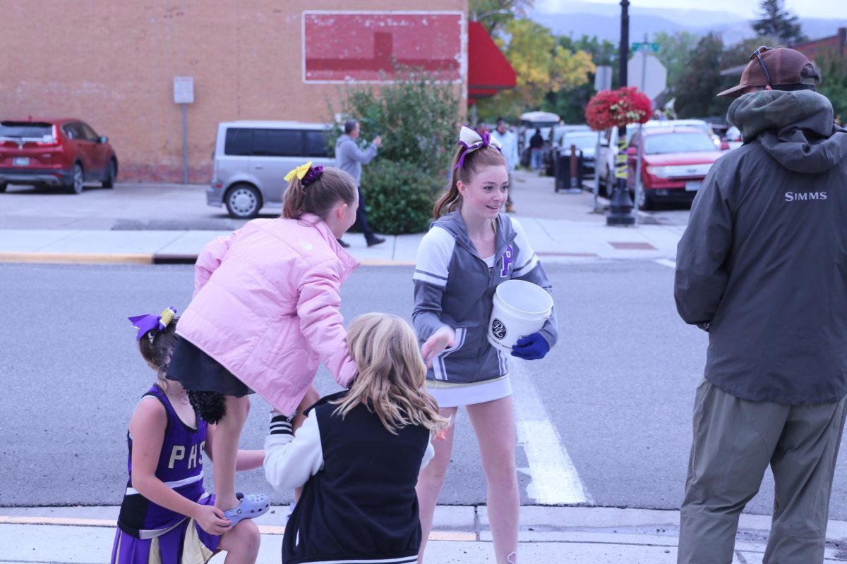 Senior cheerleader Savanah Burns hands out candy to one of the many onlookers during the Homecoming parade.