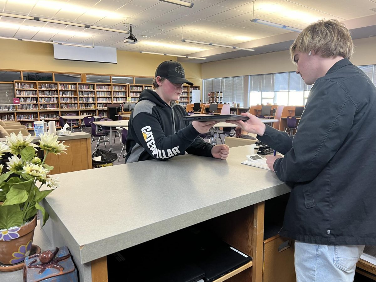 Haiden Sunderlin borrows a laptop from student librarian Isaac Hauser on March 7.  Park High does not have enough laptops to assign one to every student, so they are encouraged to bring their own devices.