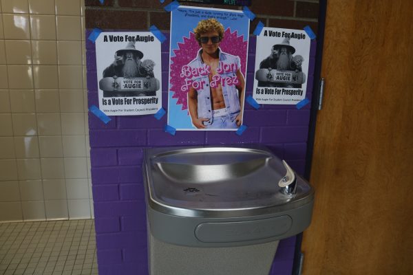Dueling campaign signs are posted outside the boys bathroom in sophomore hall.