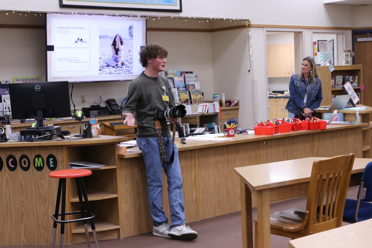 Noah Craig shows the Montana Board of Public Education his business card for his photography business.    