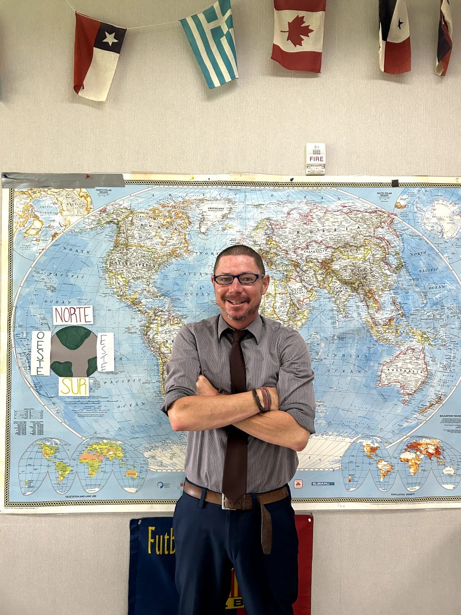 McGrath stands in front of the world map in his world languages classroom.