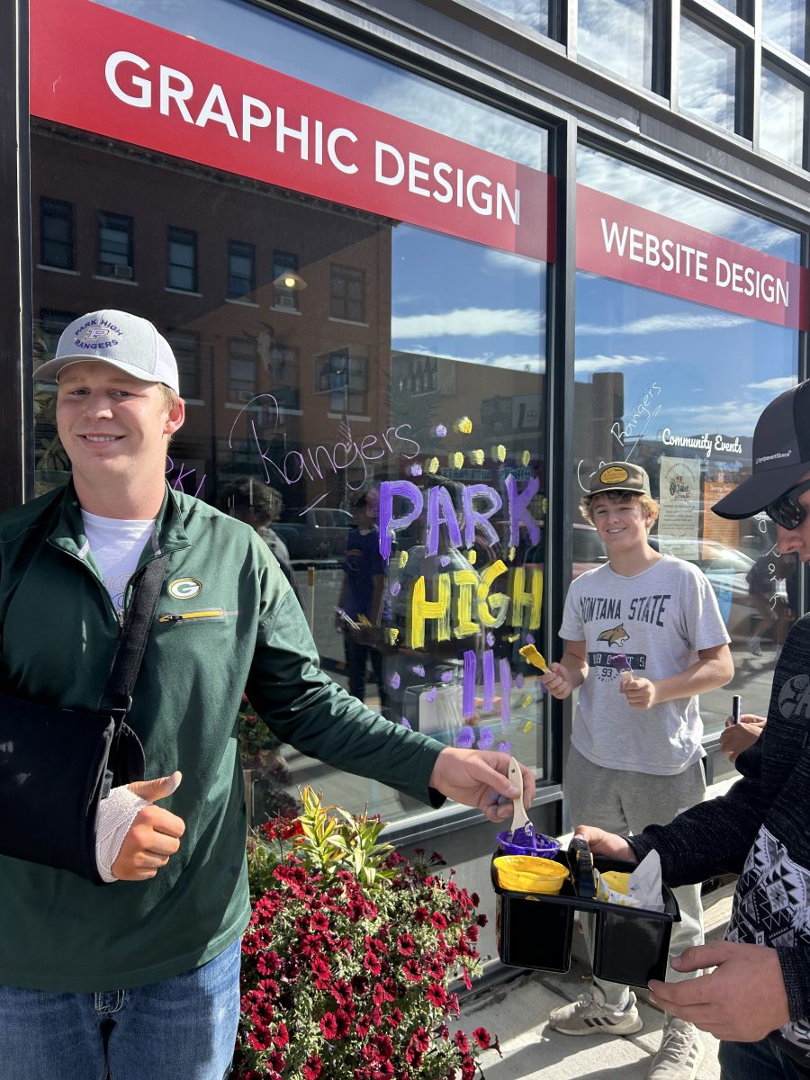 Hansford Tewell and Lliam Edwards paint on the windows of Livingston businesses to bathe the town in Purple and Gold.