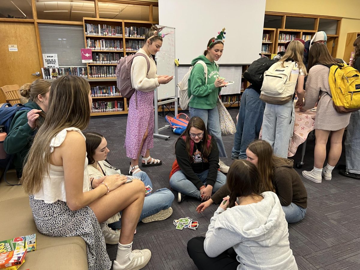 A group of junior girls plays Uno while others decorate cookies during lunch.